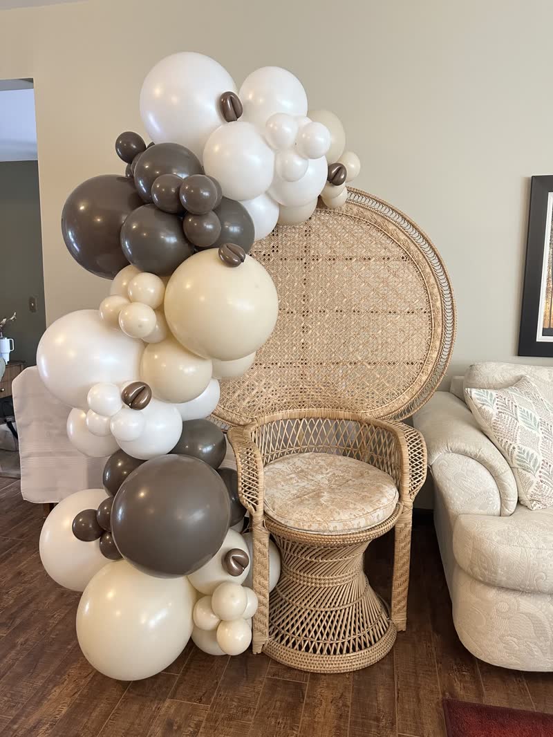 Neutral balloon garland beside a rattan chair at a Winnipeg celebration